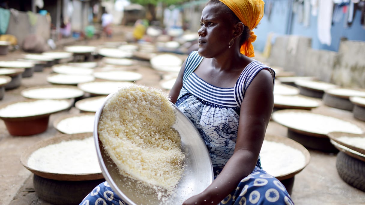 À Abidjan, une femme tamise de la farine de manioc pour la préparation de l'attiéké, un classique de la cuisine ivoirienne