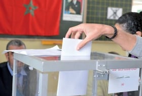 Une urne transparente reçoit un bulletin de vote.