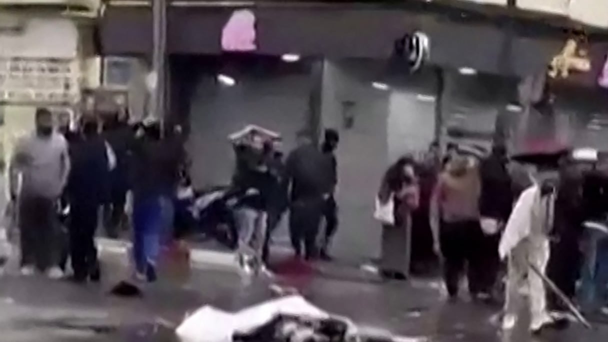 Une capture vidéo à partir d'images publiées sur les réseaux sociaux le 13 avril 2026, montrant des passants debout près d'un corps recouvert gisant au milieu d'une rue à Blida.