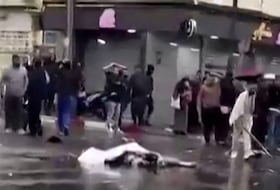 Une capture vidéo à partir d'images publiées sur les réseaux sociaux le 13 avril 2026, montrant des passants debout près d'un corps recouvert gisant au milieu d'une rue à Blida.